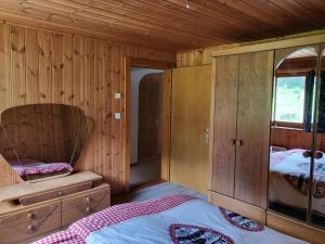 a bedroom with wooden walls and a bed and a mirror at Tga Sulai e Glina in Rona +9 photos