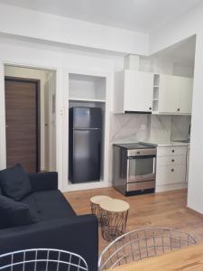 a living room with a black couch and a kitchen at Apartment 34 in Kalamata