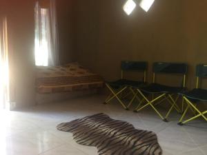 a room with chairs and a bed and a rug at De Ikut Bojo Homestay in Magelang