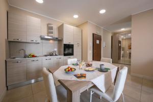 cocina con mesa con sillas blancas y comedor en Palazzo dei Delfini Apartments - Happy Rentals, en Catania