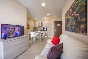 sala de estar con sofá blanco y TV de pantalla plana en Palazzo dei Delfini Apartments - Happy Rentals, en Catania