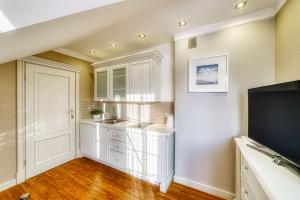 een keuken met witte kasten en een flatscreen-tv bij Perla Mare Apartamenty in Krynica Morska