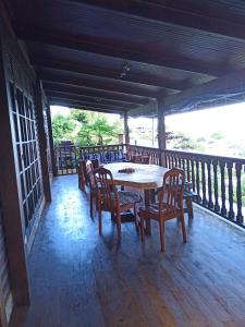 a wooden porch with a table and chairs on a deck at Enzo lodge chambre tipanier in Papawa