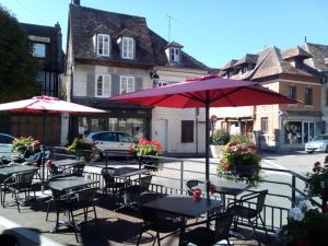 a group of tables and chairs with umbrellas on a street at La maisonnette in Les Andelys