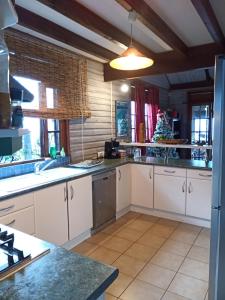 a kitchen with white cabinets and a counter top at Enzo lodge chambre tipanier in Papawa