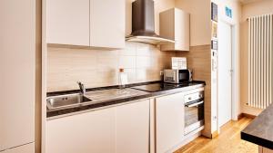 a kitchen with white cabinets and a sink and a microwave at Italianway Comfort - Salasco 18 in Milan