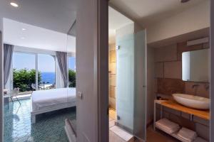 a bathroom with a sink and a bedroom with a view at Hotel Montemare in Positano