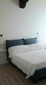 een bed met witte lakens en een blauw hoofdeinde bij La casa nel borgo in Parma