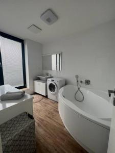 a white bathroom with a tub and a washing machine at Rezidencia Kmeťova so súkromným parkovaním zdarma, 5 min pešo do centra in Košice