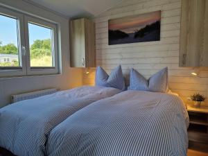 ein großes weißes Bett in einem Schlafzimmer mit zwei Fenstern in der Unterkunft Lotse 01 in Neustadt in Holstein