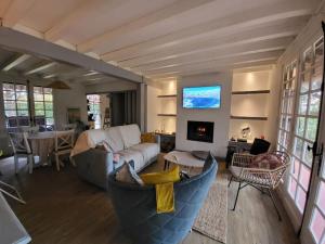 a living room with a couch and a tv at Fermette Landaise près de l'Océan et du lac marin in Vieux-Boucau-les-Bains