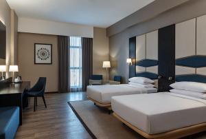 Habitación de hotel con 2 camas y escritorio en Four Points by Sheraton Production City, Dubai en Dubái