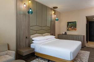 1 dormitorio con 1 cama blanca y 1 silla en Four Points by Sheraton Production City, Dubai en Dubái