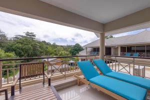 un balcón con 2 sillones azules. en Sahaj Holiday Apartments en Baie Sainte Anne
