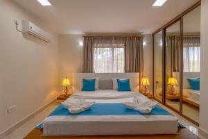 a bedroom with a large bed with blue pillows at Sahaj Holiday Apartments in Baie Sainte Anne