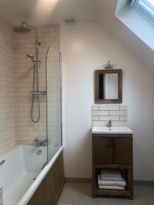 a bathroom with a bath tub and a sink at Sandyhill Guest House - Westport in Westport