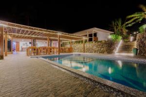 a swimming pool in front of a house at night at Thalassa Dive Resort Lembeh in Airtembago