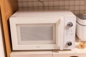 a white microwave oven sitting on a shelf at Ikebukuro Max14ppl 6bedrooms 11beds 1200sqft in Tokyo