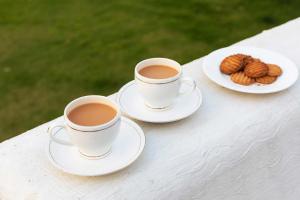 two cups of coffee and a plate of cookies on a table at StayVista at Jodhpur House - 3 BR Pet friendly Cozy villa in Manali in Manāli +20 photos