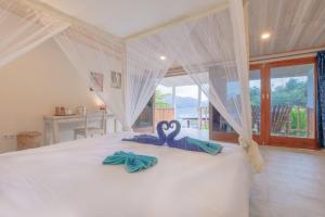 two swans towels sitting on a bed in a bedroom at Thalassa Dive Resort Lembeh in Airtembago