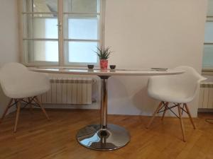 a table with two white chairs and a table with a plant on it at Apartment Rahela in Zagreb