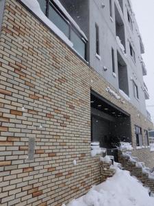 a brick building with snow on the side of it at Mountainside Palace in Niseko