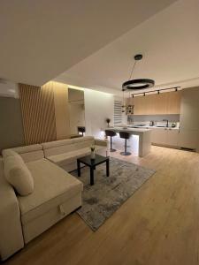 a living room with a white couch and a kitchen at Apartments Dolarevic in Sarajevo