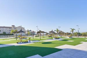 een park met gras, parasols en palmbomen bij Luxurious Two Bed in Torrox