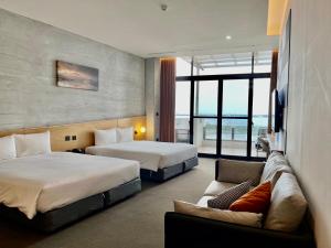 ein Hotelzimmer mit 2 Betten und einem Sofa in der Unterkunft 緩慢大鵬灣 in Donggang