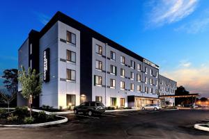 un edificio blanco y negro con un coche aparcado en un aparcamiento en Courtyard by Marriott Deptford, en Almonesson