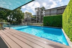 a swimming pool with a wooden deck next to a building at Stylish Apartment w/ inverter 1km 2Hyde Park in Johannesburg