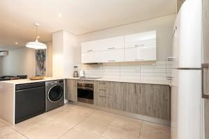 a kitchen with a washer and dryer in it at Stylish Apartment w/ inverter 1km 2Hyde Park in Johannesburg
