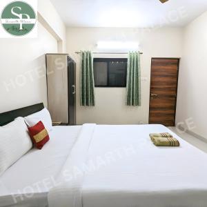Hotel SAMARTH PALACE في ماهاباليشوار: غرفة نوم بسرير ابيض كبير ونافذة