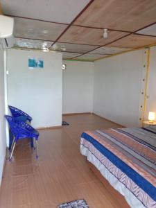 1 dormitorio con 1 cama y 1 silla azul en Friendly losmen, en Lagudri