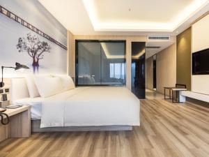 um quarto com uma grande cama branca e uma televisão em GreenTree Eastern Hotel Shenzhen Pinghu Hua'nan City Hehua Subway Station em Longgang