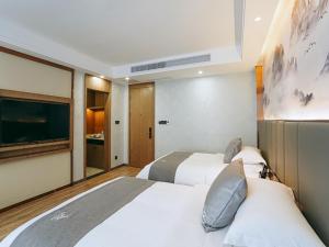 a bedroom with two beds and a flat screen tv at GreenTree Eastern Hotel Anshun Anshun Zhenning Huangguoshu in Zhenning