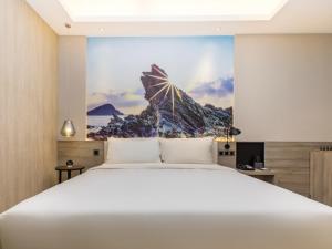 um quarto com uma grande cama branca com um quadro na parede em GreenTree Eastern Hotel Shenzhen Pinghu Hua'nan City Hehua Subway Station em Longgang