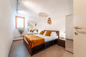 Tremezzina Charming Apartment by Wonderful Italy في تريميزو: غرفة نوم بسرير كبير مع بطانية برتقالية