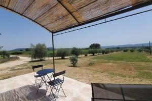 a patio with a table and chairs and a view of a field at Rêve en Lubéron in Lauris