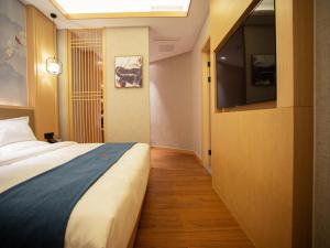 um quarto de hotel com uma cama e uma televisão de ecrã plano em GreenTree Eastern Hotel Xinjiang Urumqi Renmin Road em Ürümqi