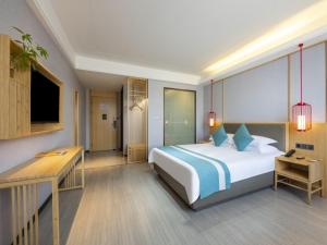um quarto com uma grande cama branca e uma secretária em GreenTree Eastern Hotel Chuzhou Government East Garden Road em Chuzhou