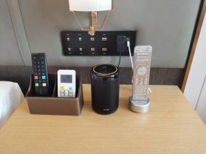 une table avec des télécommandes posées sur un lit dans l'établissement GreenTree Eastern Guangxi Baise Wuzhong Sports Center High-Speed Railway Station, à Qitang