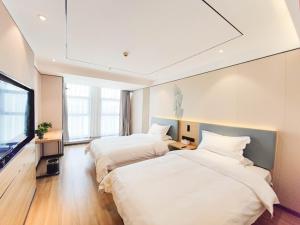 a hotel room with two beds and a flat screen tv at GreenTree Inn Lanzhou Zhongchuan Airport in Hejialiang +4 photos