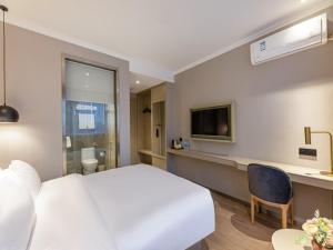 um quarto de hotel com uma cama branca e uma televisão em Gya Hotel Suzhou Hanshan Temple Binhe Road em Suzhou