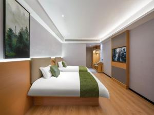 1 dormitorio con 1 cama blanca grande con detalles verdes en Vatica Hotel Shuyang Central Mall Nanjing Road, en Shuyang