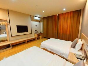 a hotel room with two beds and a flat screen tv at Geli Hotel Xuzhou Government Olympic Sports Center in Xuzhou