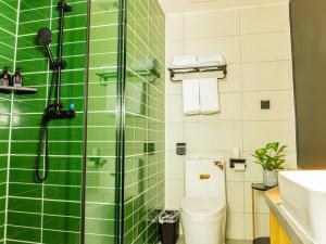 een groene betegelde badkamer met een toilet en een douche bij GreenTree Inn Express Hotel Fuyang Development Zone Oriental Pearl in Fuyang
