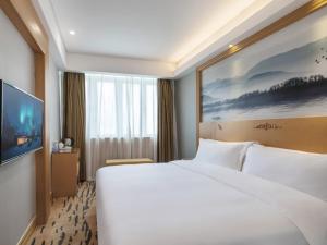 una camera d'albergo con un grande letto bianco e una TV di GreenTree Eastern Hotel Shenzhen Futian Civic Center Jingtan Subway Station a Shenzhen