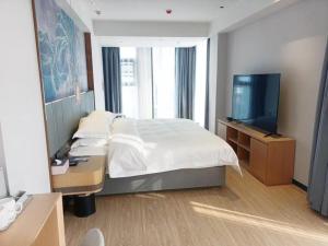 a bedroom with a bed and a flat screen tv at GreenTree Eastern Hotel Jiangsu Wanda Plaza Ocean University Huangguoshan in Lianyungang