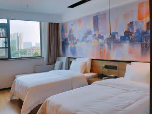 a hotel room with two beds and a painting on the wall at VX Hotel Fuyang Railway Station East Beijing Road in Fuyang